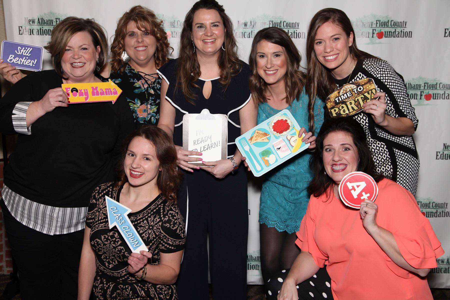 Group of teachers posing in a photo booth with education related props